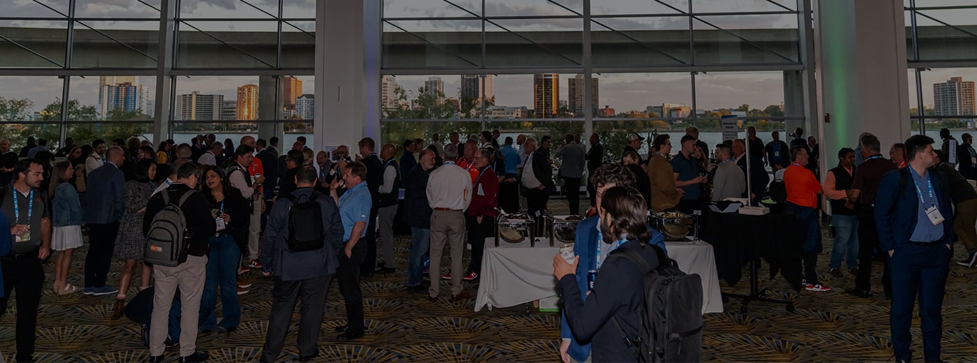 A large group of people gathered in a spacious room, engaged in conversation and networking