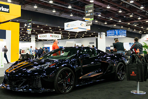 A black sports car with an aerodynamic shape, displayed prominently on expo hall